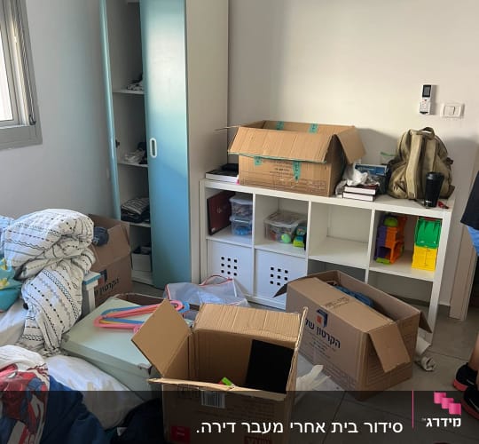 חדר עם קופסאות קרטון פתוחות ומדפים לארגון